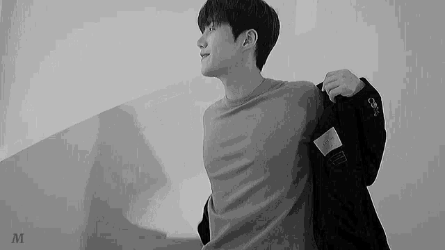 a black and white photo of a young man wearing a jacket .