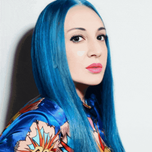 a woman with long blue hair is wearing a colorful jacket