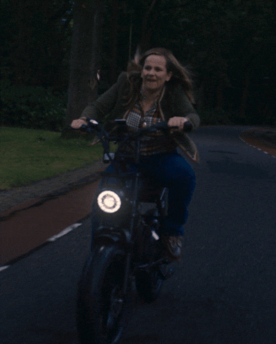 a woman screams while riding a motorcycle with a light on