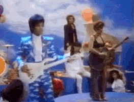 a man in a blue suit is playing a guitar in front of a crowd .
