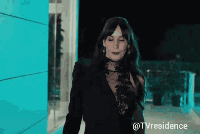a woman in a black dress is standing in front of a blue building with the hashtag tvresidence on the bottom