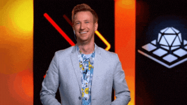 a man in a suit and floral shirt is smiling in front of a cube .