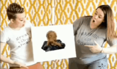 a man and a woman are standing next to each other holding a picture of a man covering his face .