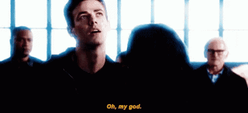a man and a woman are standing next to each other in front of a window and the man is talking to the woman .