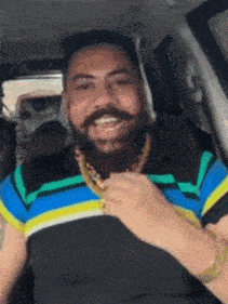 a man with a beard wearing a striped shirt and a gold chain