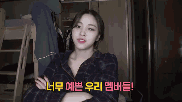 a woman in a plaid shirt is talking in a room with korean writing behind her
