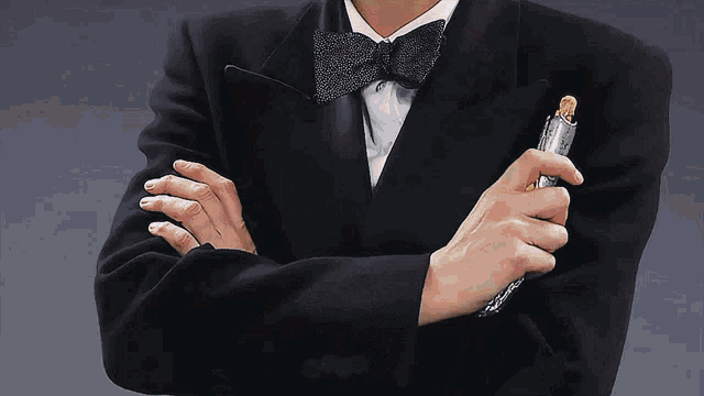 a man in a tuxedo with a bow tie holds a lighter