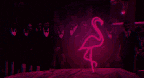 a green flamingo is painted on a wall in the dark