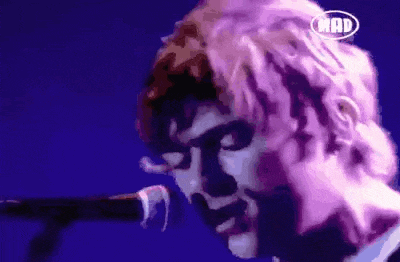 a close up of a person singing into a microphone with the word mad on the corner