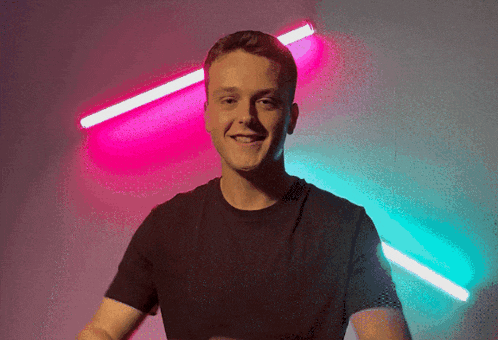 a man in a black shirt stands in front of a pink and blue light
