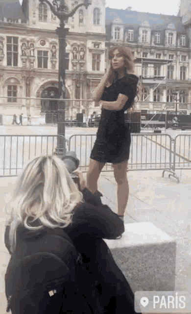 a woman taking a picture of a woman in a black dress in paris