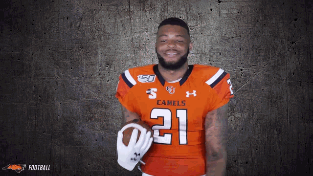 a man in an orange jersey with the number 21 on it holds a football