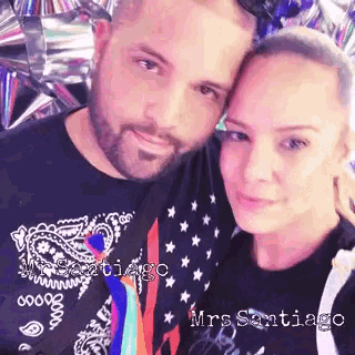 a man and a woman are posing for a picture and the woman is wearing a black shirt that says mrs. santiago