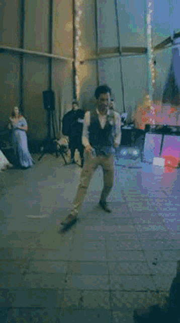 a man is dancing on a dance floor with a woman in a dress behind him .