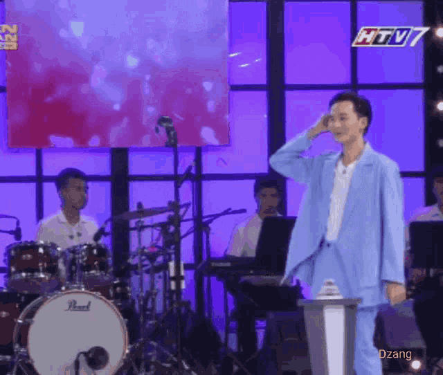 a man in a blue suit stands in front of a drum set and a pearl drum
