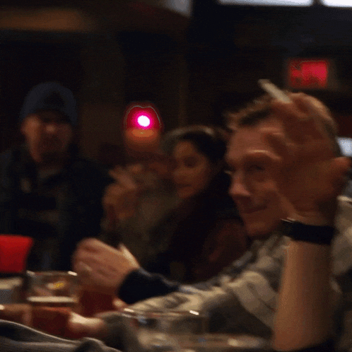 a group of people are sitting around a table with a red light behind them