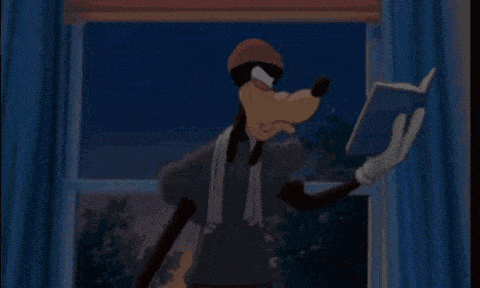 goofy is reading a book in front of a window while wearing a towel around his neck .