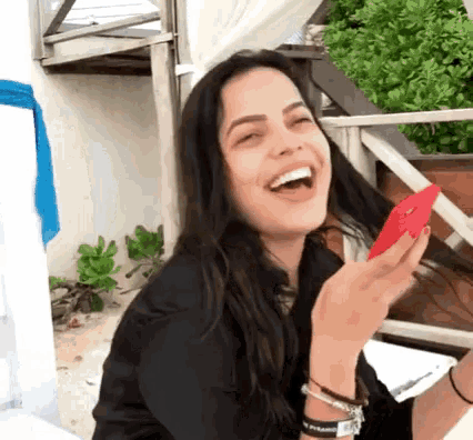 a woman is laughing while holding a cell phone .