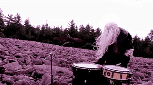 a person playing drums in a rocky field