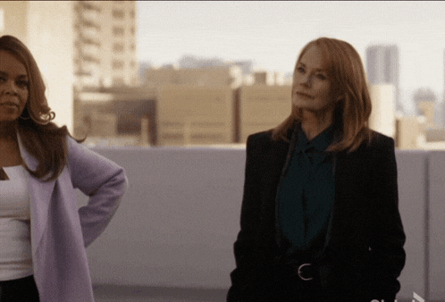 two women standing next to each other with one wearing a purple coat