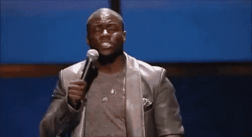 a man in a leather jacket is holding a microphone and making a face .