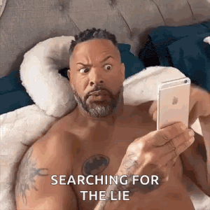 a shirtless man is laying on a bed looking at his phone .