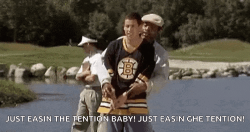 a man in a boston bruins jersey is being helped by a man in a white hat .