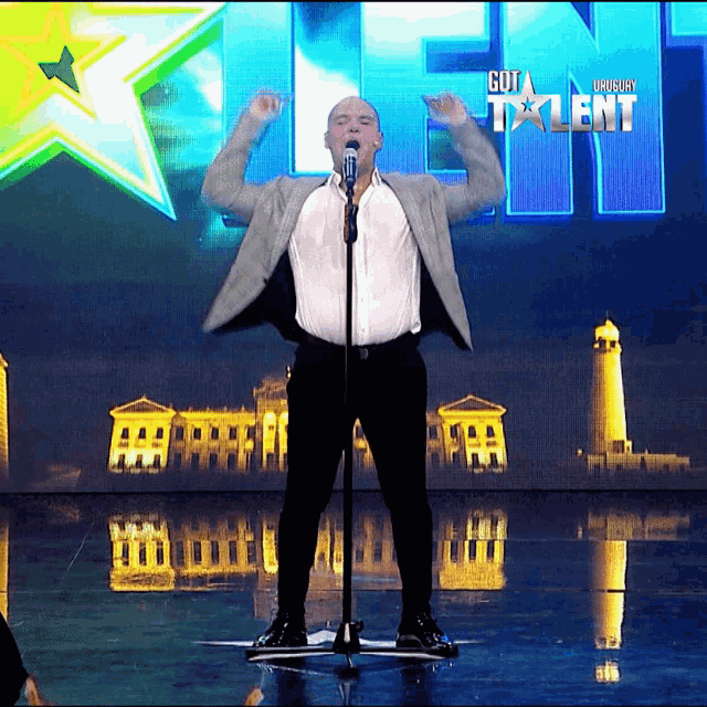 a man is singing into a microphone in front of a screen that says got talent