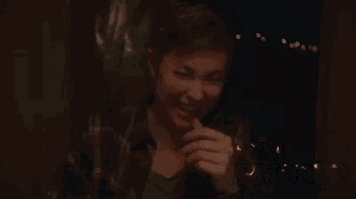 a woman covering her mouth with her hand and the words kim rhodes behind her