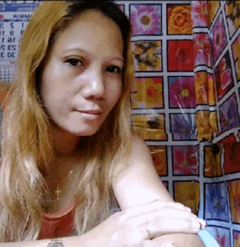 a woman is sitting in front of a wall with flowers on it and a calendar that says roses