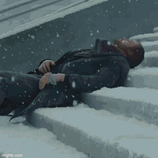 a man is laying on the snow covered stairs .