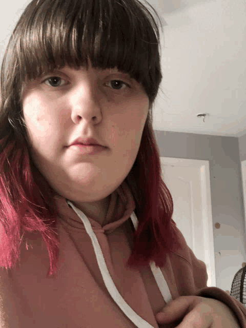 a girl with red hair and a pink hoodie