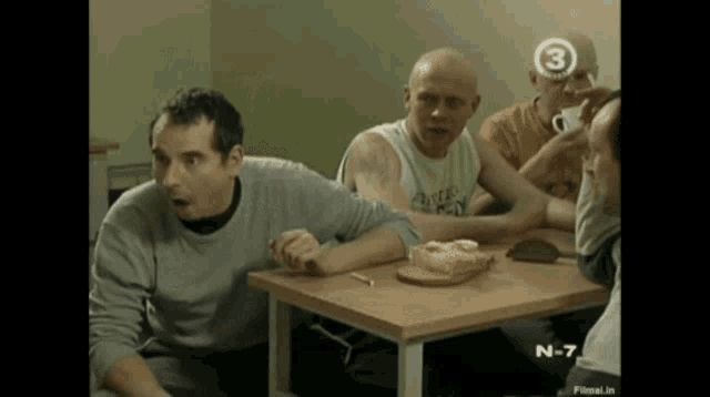 a group of men are sitting at a table with the number 3 on their heads