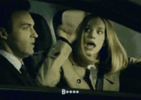 a man and a woman are sitting in a car and the woman is screaming