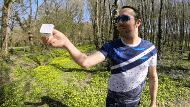a man wearing sunglasses and a blue shirt is holding a container of yogurt