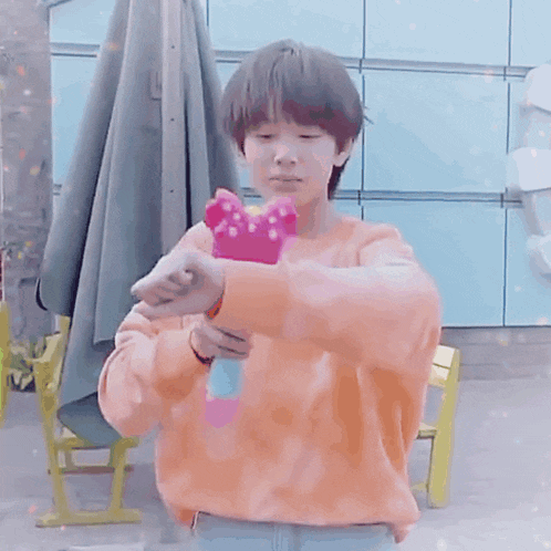 a boy wearing an orange sweater is surrounded by hearts and a unicorn