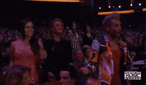 a man in a red jacket stands in the crowd at the american music awards