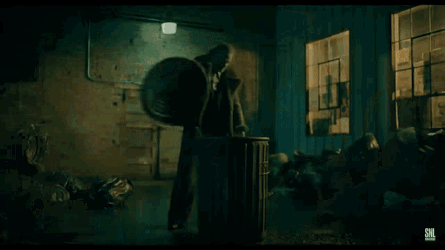 a man is kicking a trash can in a dark room with a snl logo in the corner