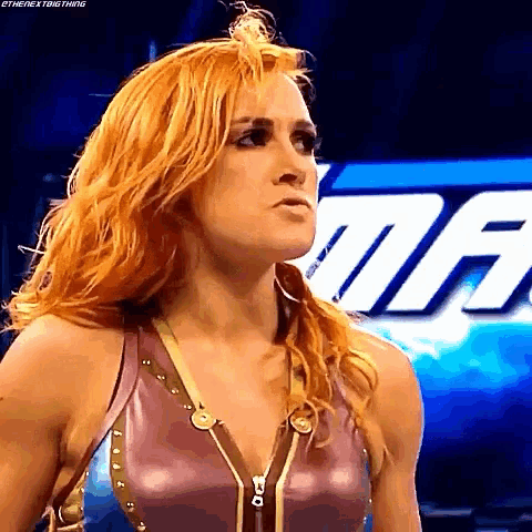 a woman with red hair is standing in front of a sign that says the next big thing .