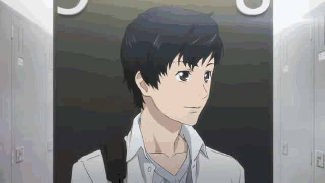 a man in a white shirt is standing in a hallway with lockers and a sign that says u