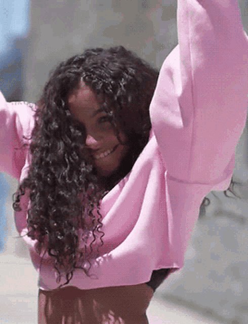a woman with curly hair is wearing a pink crop top