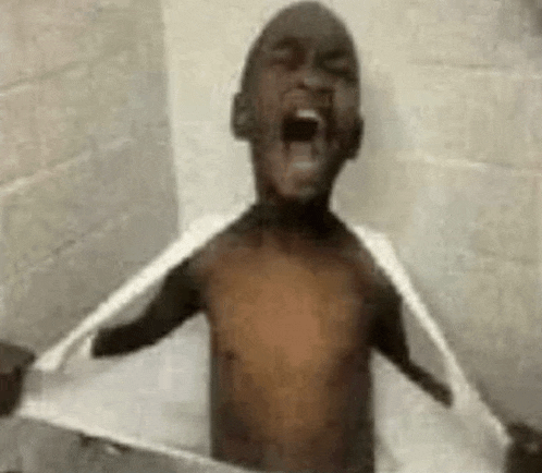 a shirtless young boy is taking a bath in a bathtub .