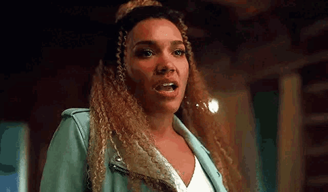 a woman with curly hair is wearing a blue jacket and white shirt .