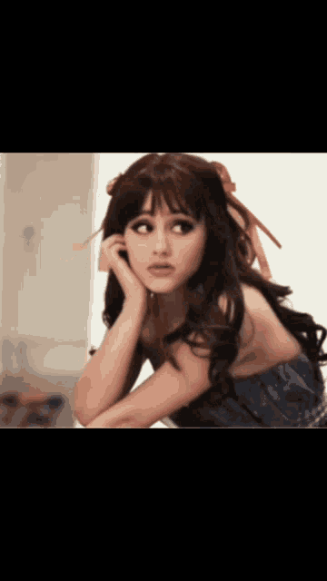 a woman with a bow in her hair is looking at the camera