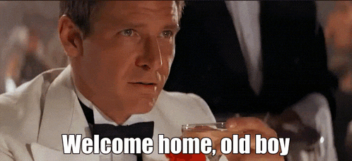 a man in a tuxedo holds a glass of wine and says welcome home old boy