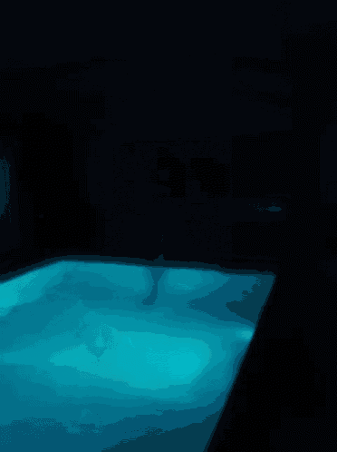 a person is swimming in a pool with a blue light