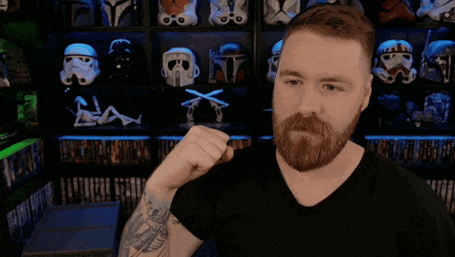 a man with tattoos on his arms is standing in front of a shelf with storm trooper helmets