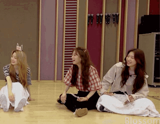 three women are sitting on the floor and the word blossom is on the bottom right