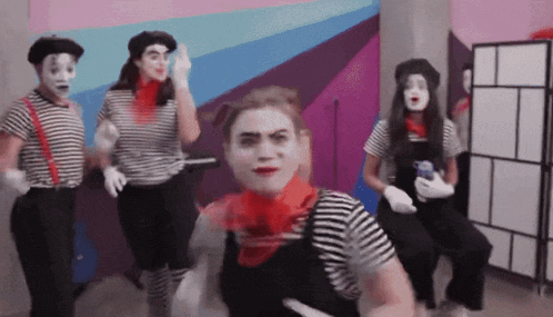 a group of people dressed up as mimes are dancing in a room
