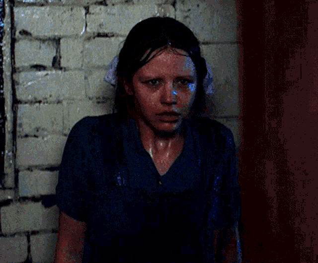a woman is standing in front of a brick wall with her face wet